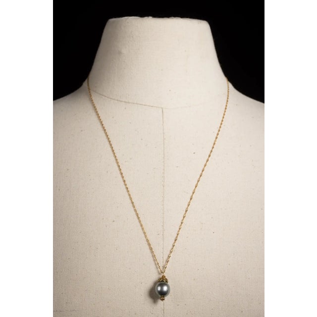An elegant 12mm Tahitian pearl pendant with three round, faceted diamonds in 18K gold at the bottom and an 18K gold end...