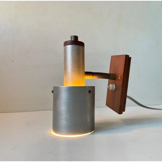 Small adjustable Wall lamp made aluminium and teak. It features an adjustable brass goose-neck and on/of switch to its...