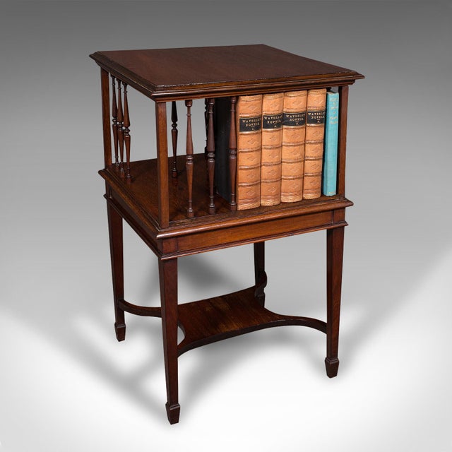 This is an antique revolving bookcase. An English, walnut rotating novel library, dating to the Edwardian period, circa...