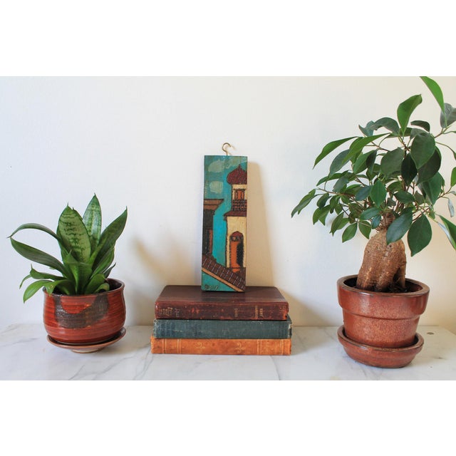 Vintage hand painted folk art wood carving features a textured impasto street scene of colonial architecture in rich teal,...