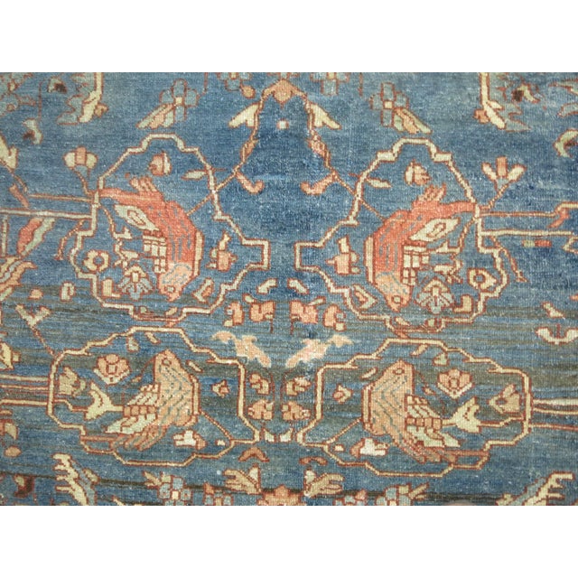 An early 20th century Persian Malayer rug. Abrashed blue field and terracotta border. A few pigeons are spotted in the...