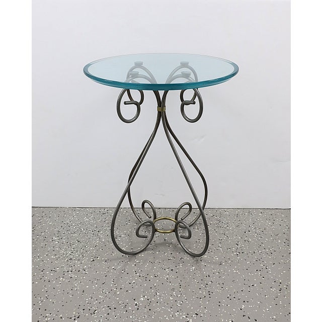 A round metal, brass, and glass side table, circa late-20th century. Table has a substantial round glass top supported by...