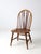 Vintage brace-back Windsor chair in the Colonial Revival style, featuring a continuous bow back with slender spindles and...