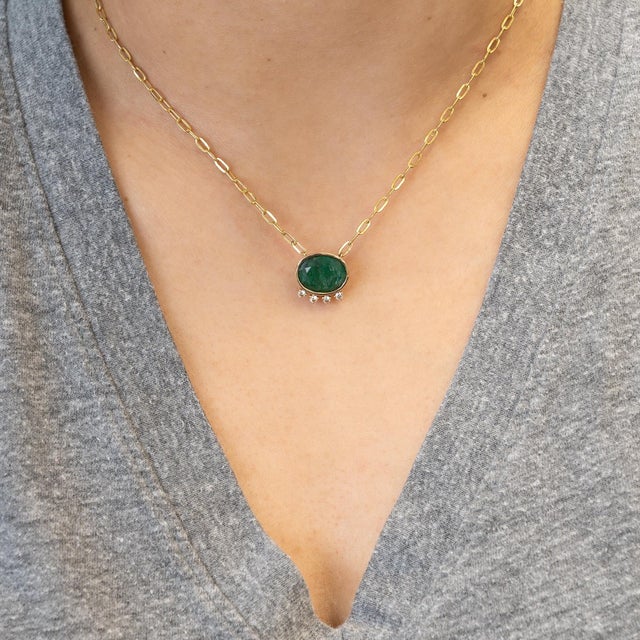 A striking 4.9 carat emerald radiates rich green brilliance, accented by shimmering natural diamonds for elevated...