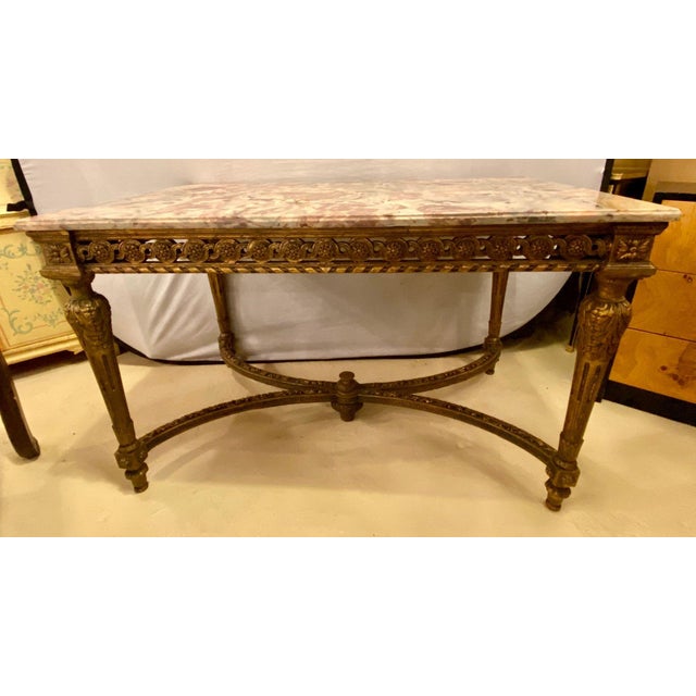 Stamped Jansen center table having a gilt base and fine pink, grey and white veined marble-top. The top having been...