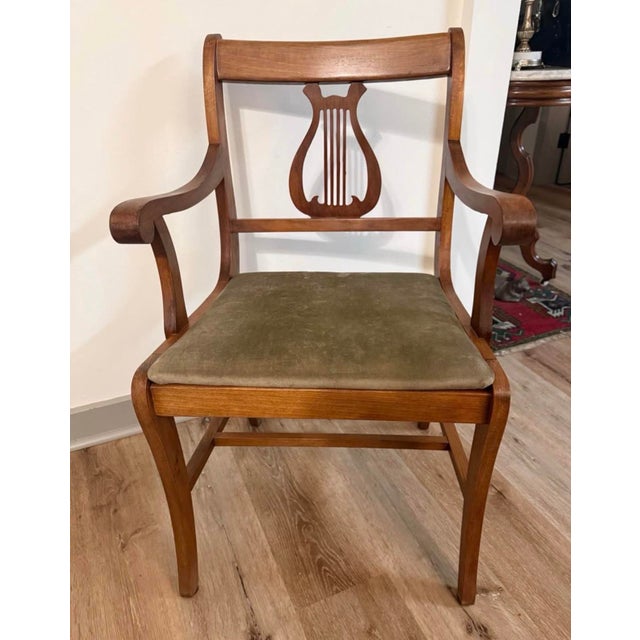Elegant vintage Duncan Phyfe style arm chair featuring the classic lyre (harp) back design, gracefully curved arms, and...