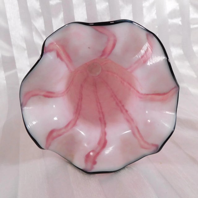 This is a Frans Welz Bohemia pink striped art glass vase with an added black rim. It hasa footed base and ruffled top...