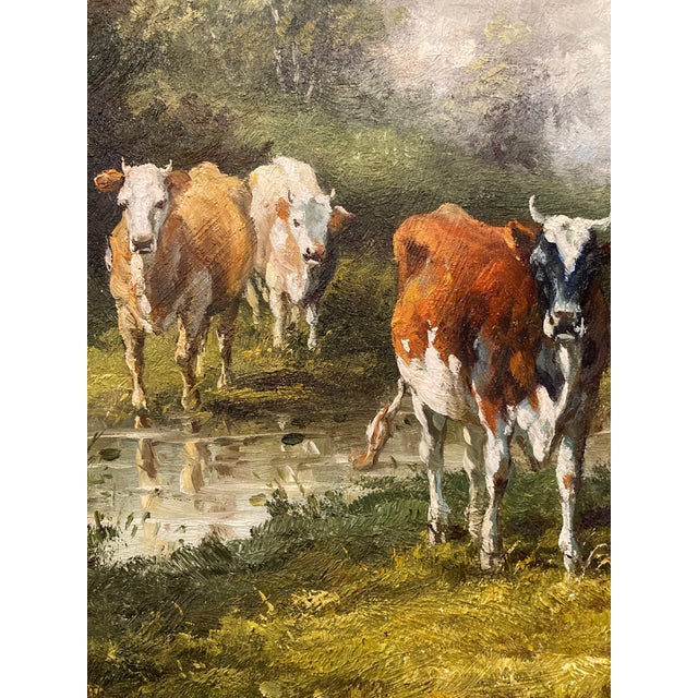 A charming antique oil on board painting depicting three cows in a tranquil pastoral landscape, believed to date from the...