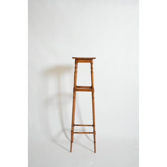 Light wood faux bamboo pedestal table, 1900s. Light wood side table resting on four faux bamboo feet joined by two belts...