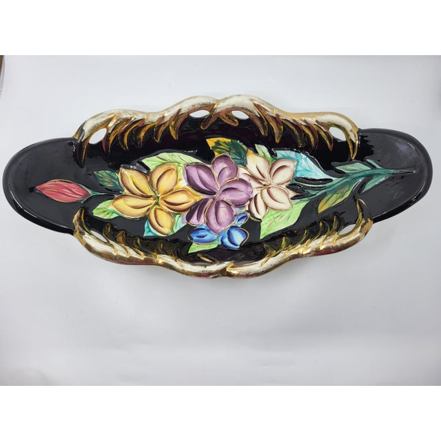 A finely hand-painted ceramic bowl, adorned with a floral motif on a black background, with a gold frame. This masterpiece...