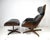 A Mid Century black leatherette and walnut swiveling high back lounge chair with matching ottoman. Each base has a...