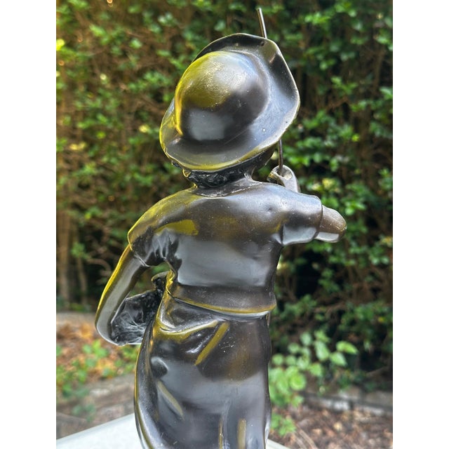 A bronze sculpture with a green patina depicting a young fisherman, signed Hippolyte François Moreau. This naturalistic...