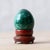 Hand-carved malachite egg with bold banding on fitted wooden stand, c.1980. Egg: 2 in tall x 1 ½ in wide; with stand: 2 ½...