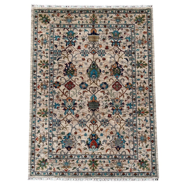 A hand-knotted area rug in the classical vase design, woven in Afghanistan on a soft ivory ground with turquoise, navy,...