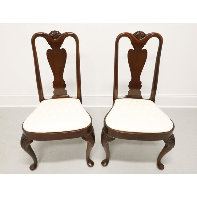A pair of Queen Anne style dining side chairs by Hickory Chair. Solid mahogany with a carved shell to center of arched...