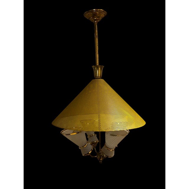This Italian chandelier from the 1950s is distinguished by a perforated yellow conical metal frame above four light points...