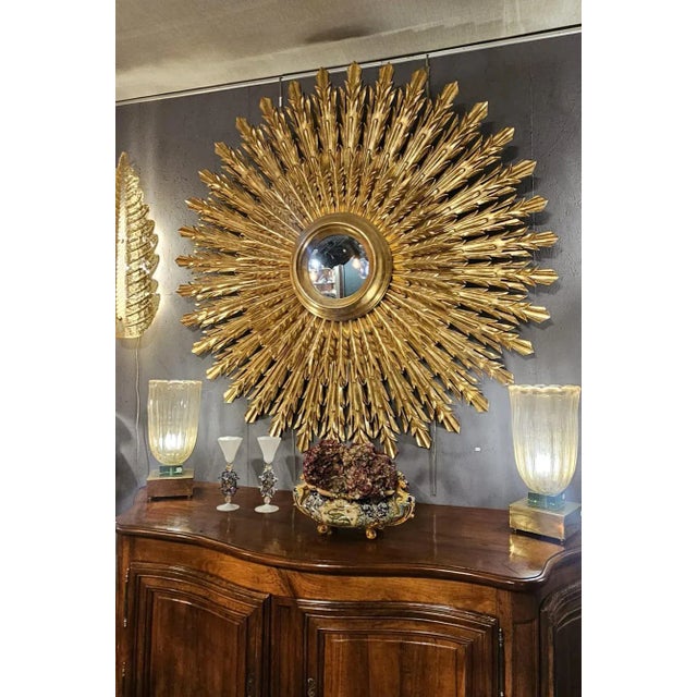 Magnificient italian style sunburst golden mirror. This exquisite piece was entirely hand-carved and features two tiers of...