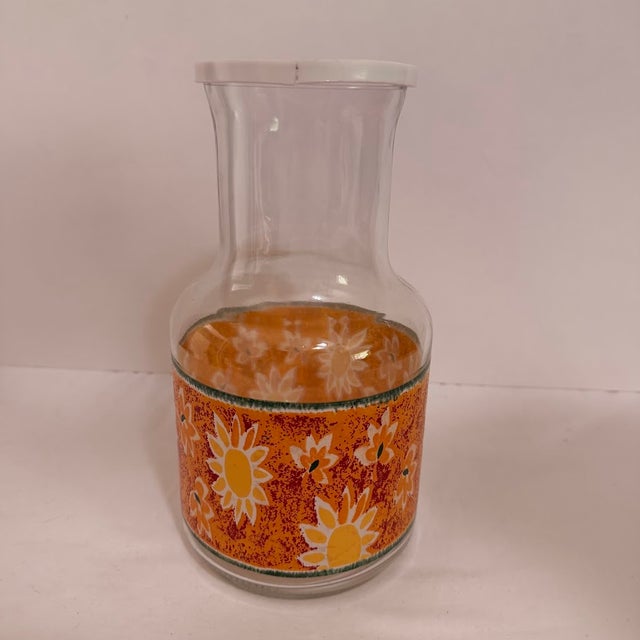 Vintage KIG Indonesia glass carafe featuring a vibrant orange and yellow sunflower floral wrap design. This retro juice...