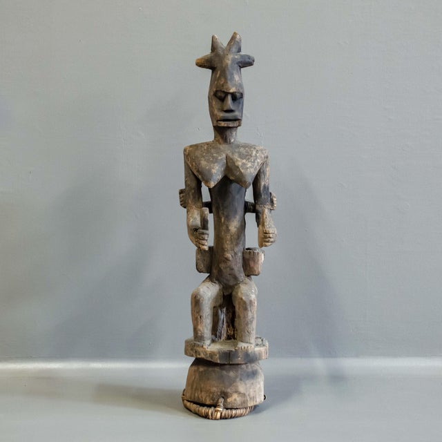 Hand carved from a single piece of wood, this vintage Nigerian figure of a mother with child on her back, rests on a small...