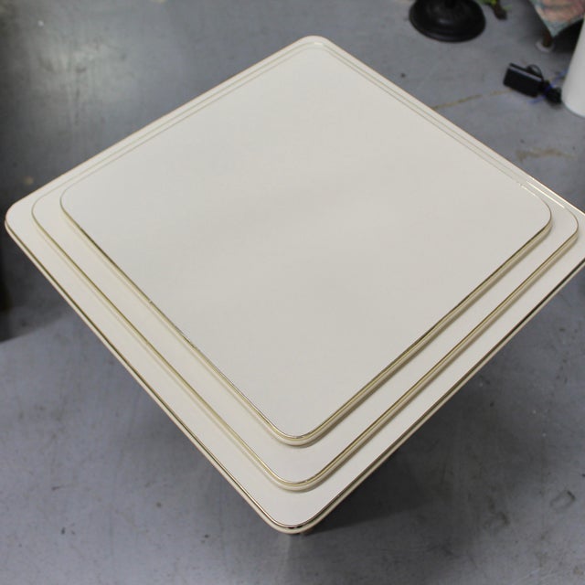 1970s cream colored pedestal column table base. Cream colored heavy laminate on composite wood with brass finish edging....