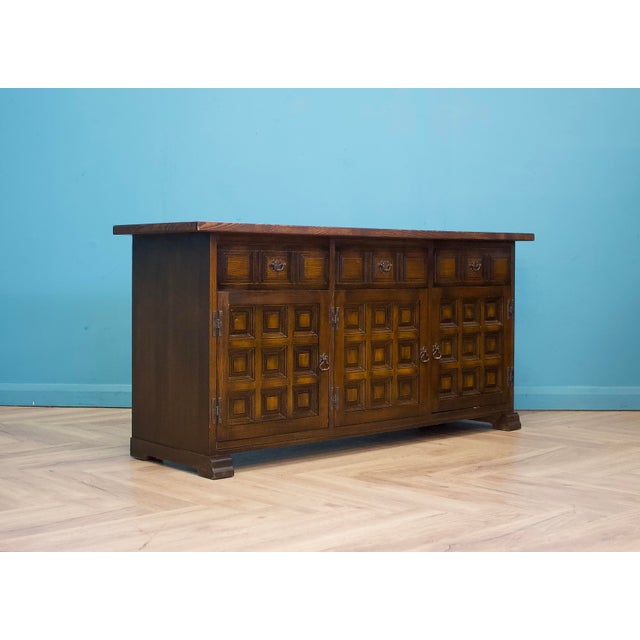 1970s Younger ‘Toledo’ sideboard in dark oak, with geometric panelled doors and carved drawer fronts. Three drawers above...