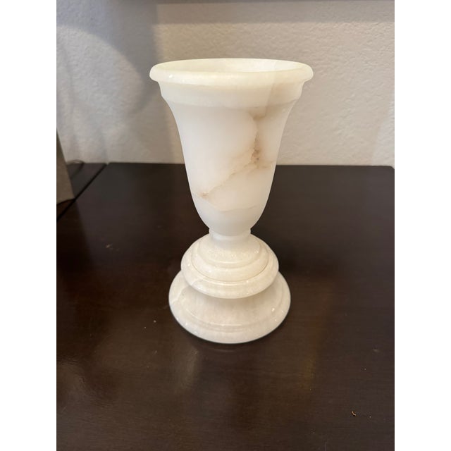 A beautifully hand-carved alabaster urn form featuring soft natural veining and a smooth, matte-polished surface. This...