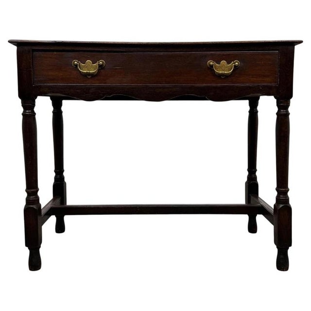 A handsome 18th-century English side table, finely crafted from oak and distinguished by its traditional turned legs,...