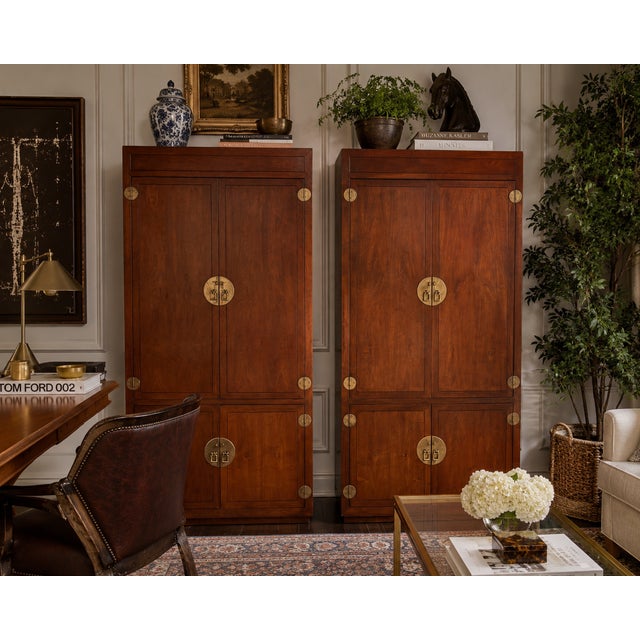 A handsome pair of Henredon Scene One campaign-style armoires crafted in beautifully figured walnut with distinctive solid...