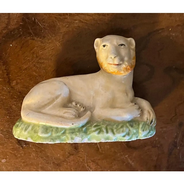 Antique early 19th century English porcelain figure of a lion posed on a grassy mound. Wonderful detail and light pink...