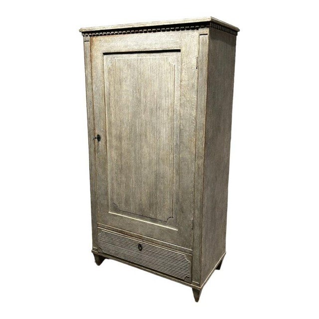 A small gustavian cabinet made of pine. The furniture has a drawer. The large door is richly decorated with a decorative...