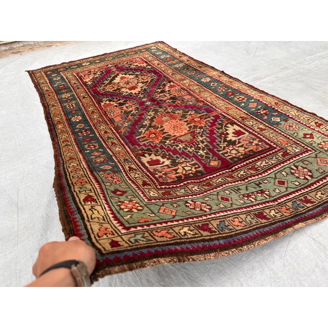This antique hand-knotted Shirvan Akstafa rug features stacked serrated star medallions in burgundy and brown, set against...