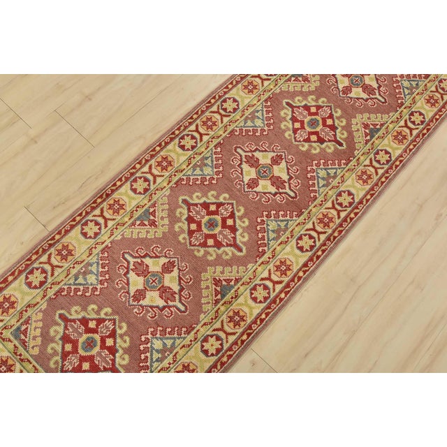 A tribal Caucasian Kazak runner hand-knotted with fine wool on a cotton foundation. This rug features a row of geometric...