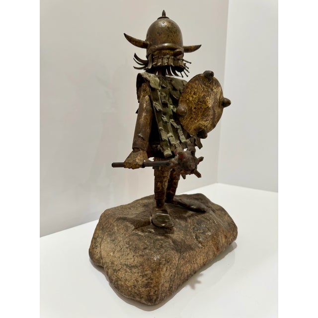 Brutalist metal sculpture depicting a whimsical Viking warrior with horned helmet, dimensional beard, layered armor, round...