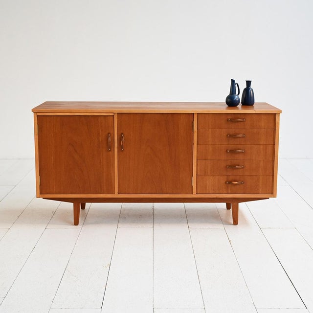 Teak sideboard with light wood details, pull-out top, hinged doors, and drawers. Scandinavian production, 1960s....