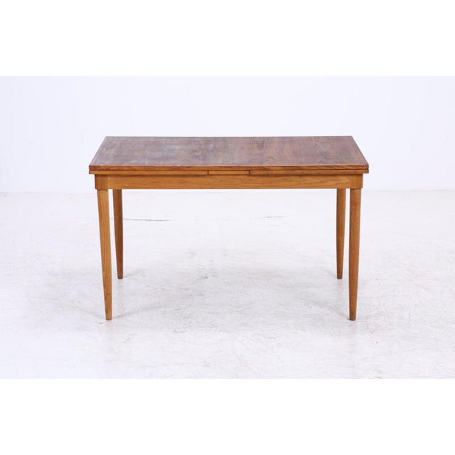 Vintage dining table with clean, straight lines and gently tapered legs. The table can be extended on both sides, offering...