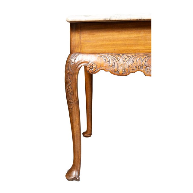 Irish mahogany console table. With a marble top with a repaired break done long ago. Carved frieze decorated with...