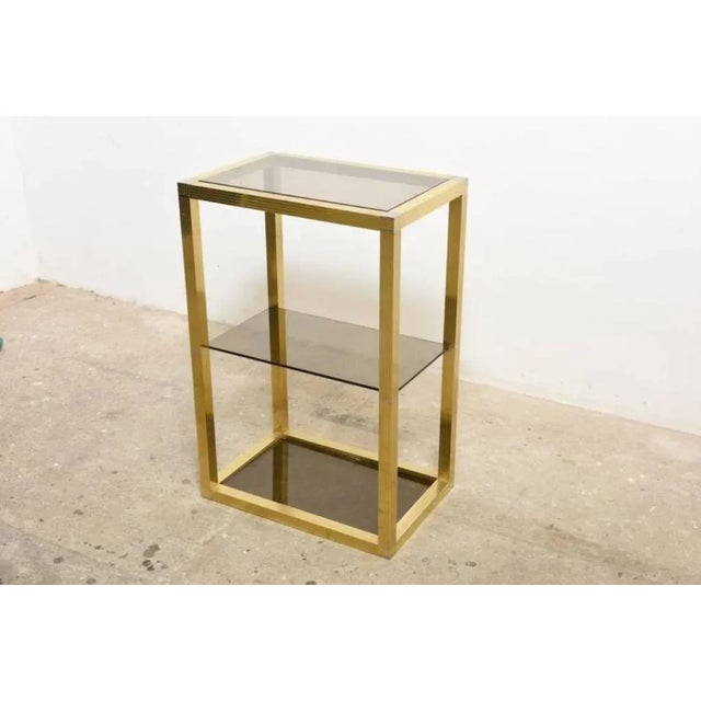 This rectangular vitrine has three smoked glass tops which are supported by a brass frame with chrome accents.