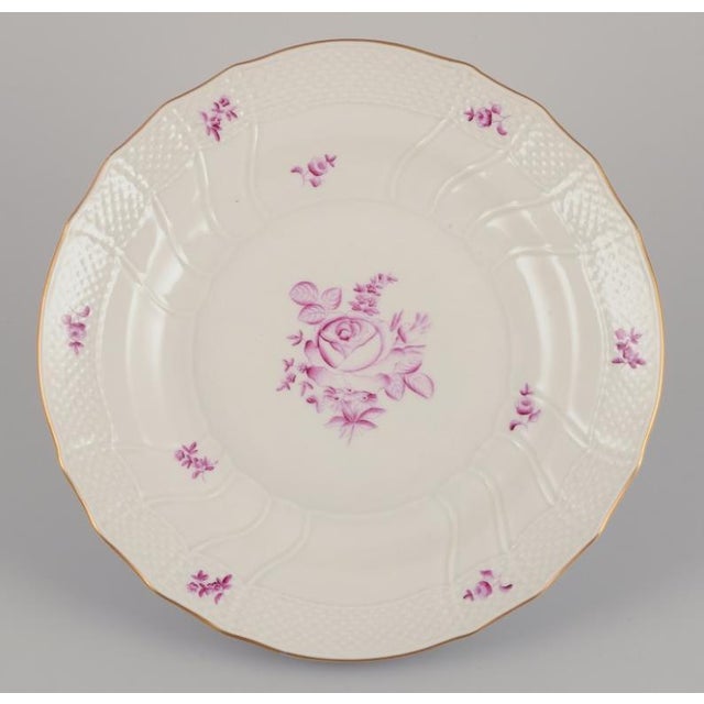 Herend, Hungary. A set of four dinner plates. Hand-painted with purple floral motifs. Gold rim. Mid-20th century. Marked....