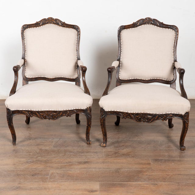 Late 19th-century pair of Swedish walnut armchairs featuring carved detailing along the backs, arms, and skirts. The...