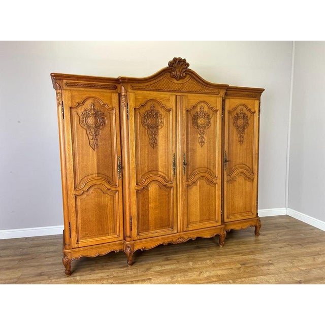 An elegant Vintage French Louis wardrobe crafted in Oak, featuring an impressive four-door design with richly carved...