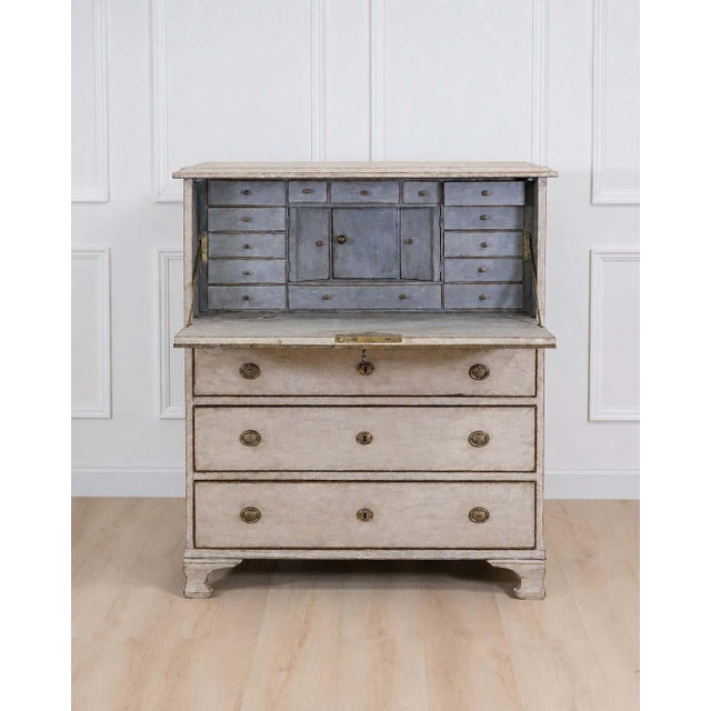 An antique Swedish bureau in antique white. This piece of furniture consists of two stacked sections. The upper section is...