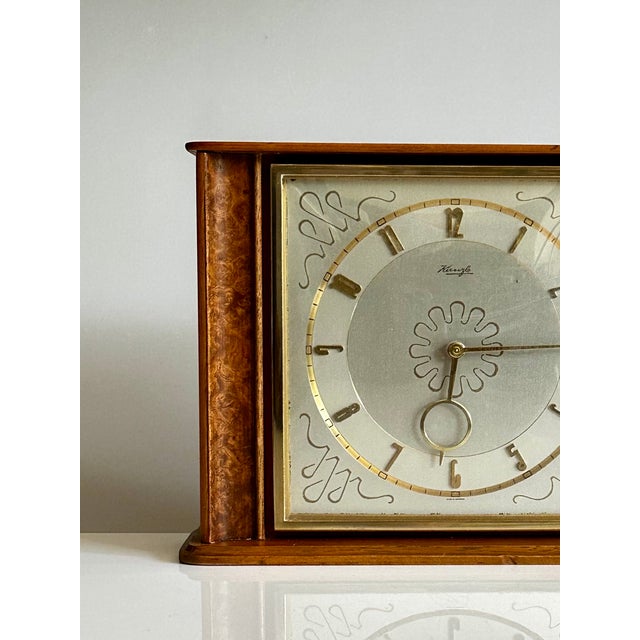 An elegant Kienzle table clock from the 1950s with a mechanical 8-day movement. It features a high-quality veneered wood...