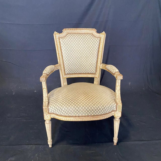 Elegant French Louis XVI period chairs with original white and gold paint. Classic diamond pattern fabric accented on all...
