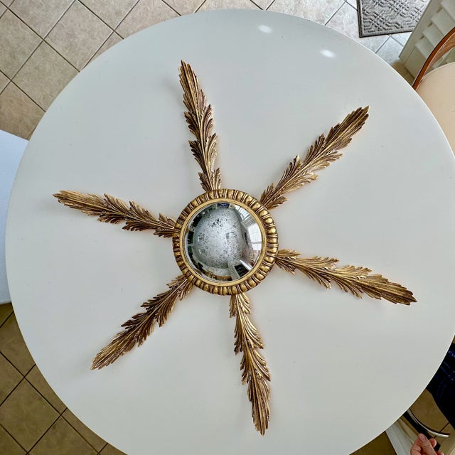 French style brass sunburst or starburst antiqued convex wall mirror with leaf shaped "rays". The brass is thick and heavy...