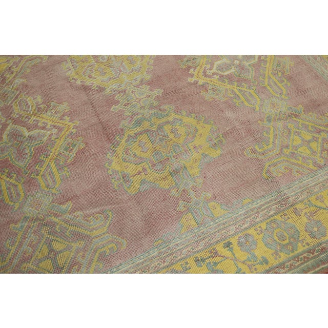 An early 20th century Turkish Oushak with an all over geometric design on aa rose field. The border is a bright yellow....