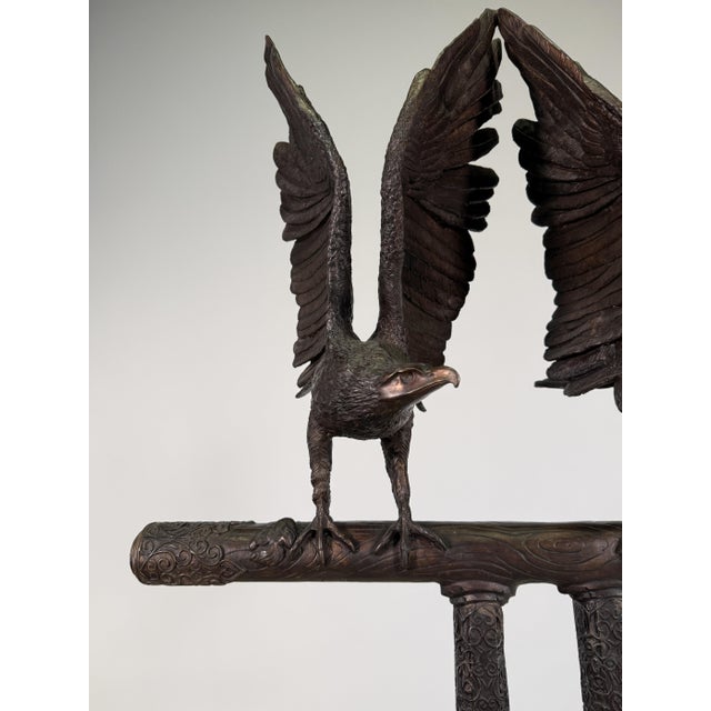 A monumental bronze sculpture featuring two eagles perched side-by-side with wings raised in a mirrored, upward-reaching...