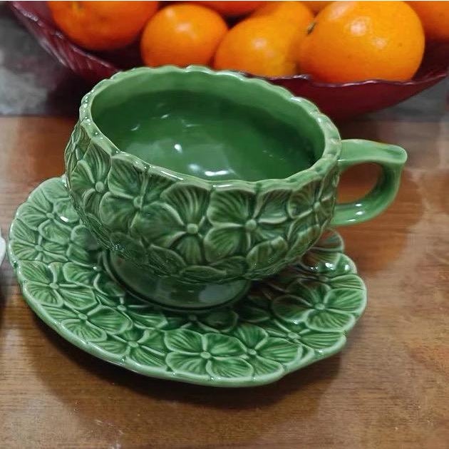 Employing a ceramic handcrafted three-dimensional relief technique, the cup and saucer are covered with hydrangea relief...