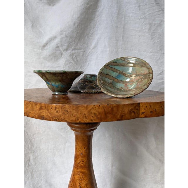 A vintage hand thrown set of three eclectic metallic raku ceramic bowls circa 1980s. A unique studio pottery set featuring...