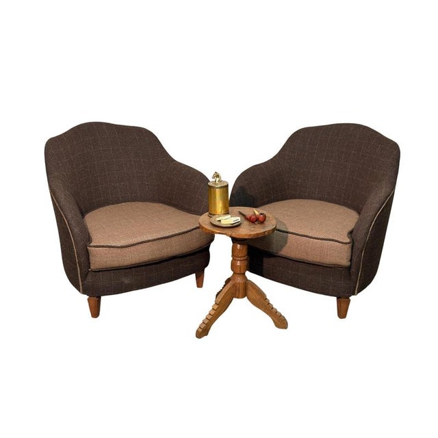 An elegant pair of 1950s armchairs, expertly restored and reupholstered with a fine wool and cashmere fabric from the...