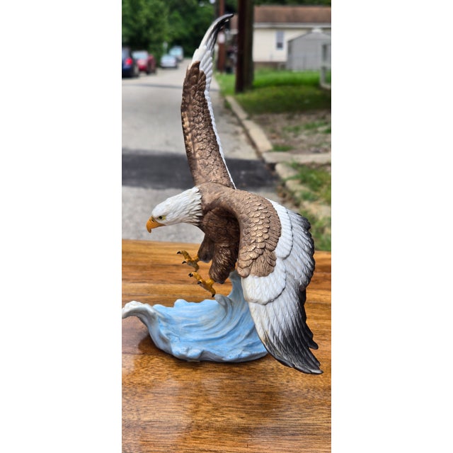Powerful and highly detailed bald eagle sculpture captured in mid-flight, with one wing dramatically extended upward and...